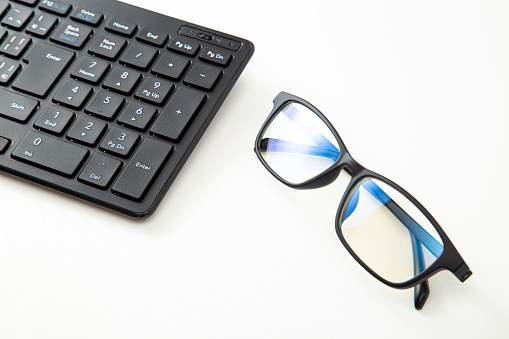 Computer keyboard and blue light blocking glasses.
