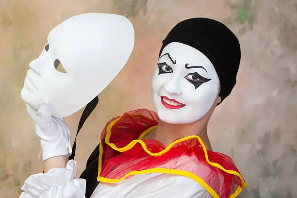 Female smiling pierrot holding a serious white face mask