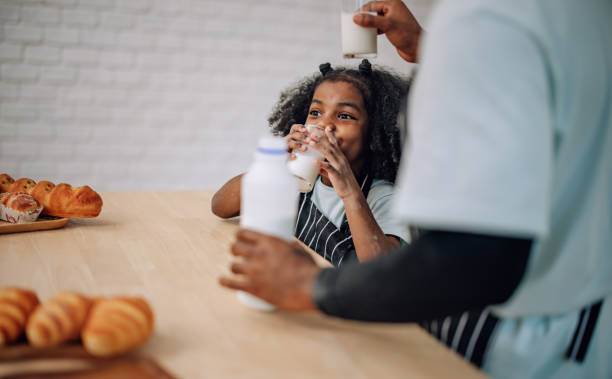 istock Father-daughter bond in kitchen, laughing, cheering milk competition, creating cherished memories. 1580076345