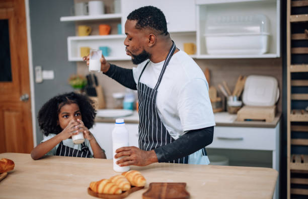 istock Father-daughter bond in kitchen, laughing, cheering milk competition, creating cherished memories. 1580076886