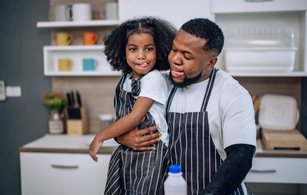 istock Father-daughter bond in kitchen, laughing, cheering milk competition, creating cherished memories. 1580080640
