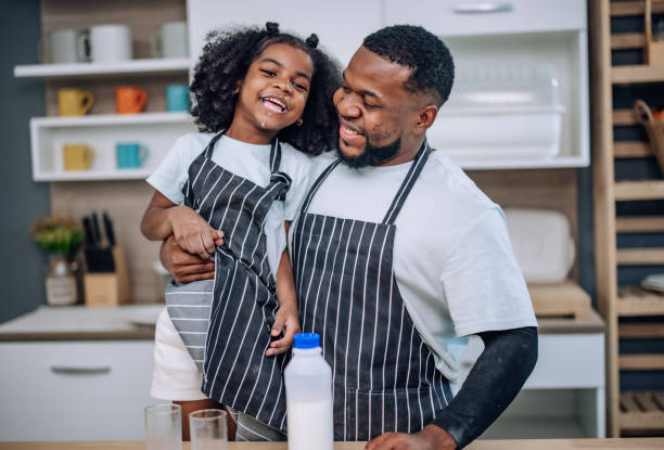 istock Father-daughter bond in kitchen, laughing, cheering milk competition, creating cherished memories. 1580080642