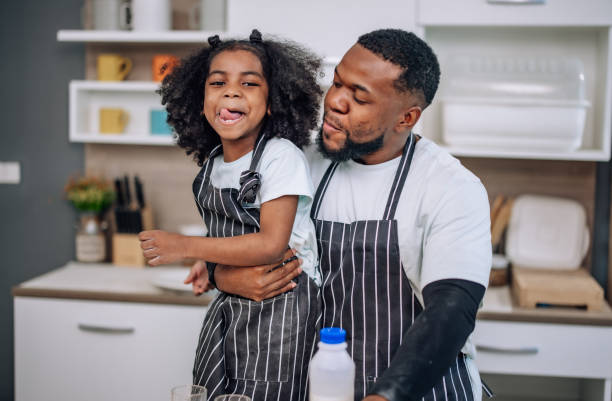istock Father-daughter bond in kitchen, laughing, cheering milk competition, creating cherished memories. 1580080643