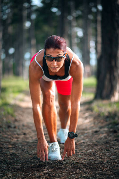 Woman jogger in ready position, training at park.