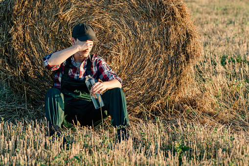 Exhausted farmer having a headache while working in the wheat field