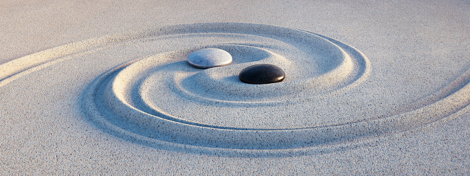 Yin Yang symbol. Motive made of stones and lines in the sand at evening sun - 3D illustration