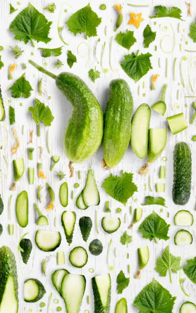 Abstract background made of Cucumber vegetable pieces, slices and leaves on wooden background.
