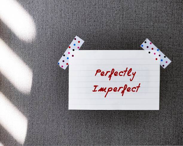 Stick note on wallpaper with handwritten text PERFECTLY IMPERFECT, concept of self acceptance, with all flaws, embracing imperfections which are often more valuable than perfections Stick note on wallpaper with handwritten text PERFECTLY IMPERFECT, concept of self acceptance, with all flaws, embracing imperfections which are often more valuable than perfections imperfection stock pictures, royalty-free photos & images