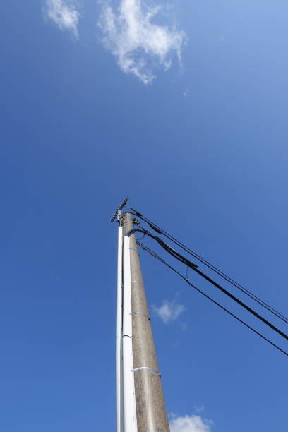 istock Optical fiber on a country road  Low angle view  Telephone and communication line fixed on a pole 1580189879