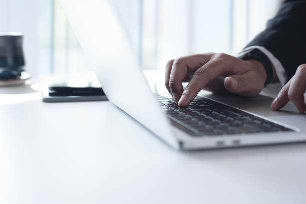 istock Businessman working on laptop computer on white office table, searching the information and browsing the internet. Corporate man online working at modern office, close up 1580237099