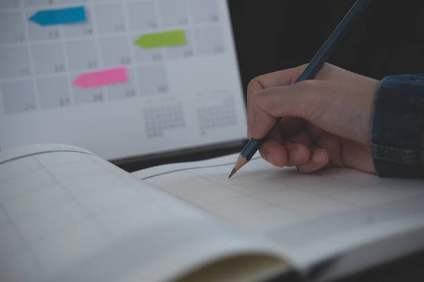 istock Event planner timetable agenda plan on year 2023 schedule event. Business woman checking timetable, taking note on calendar planner notebook on office table. Calendar event plan, work planning, mockup 1580245486
