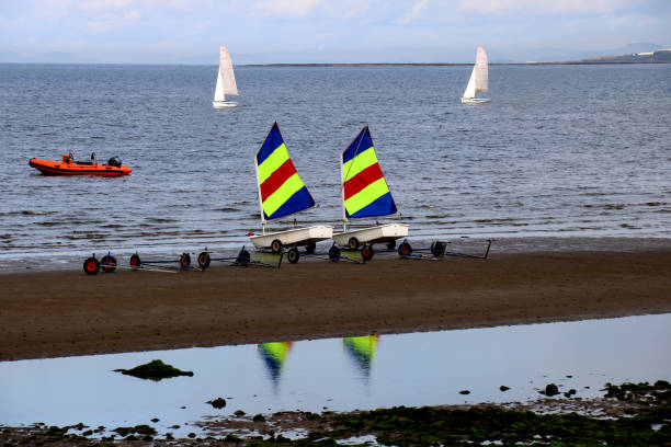 Small sailing dinghy boats with colourful sails at a coastal beach location