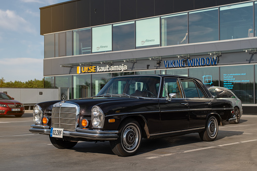 Tallinn, Estonia - July 11 2023: Vintage Mercedes-Benz 280 SE 1970 parked in Tallinn city on a sunny summer evening. Vintage car on modern city background.