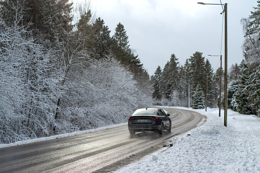 Aespa, Estonia - February 19 2023: Skoda Octavia is moving on a road covered with a snow, countryside road in a winter cloudy morning.