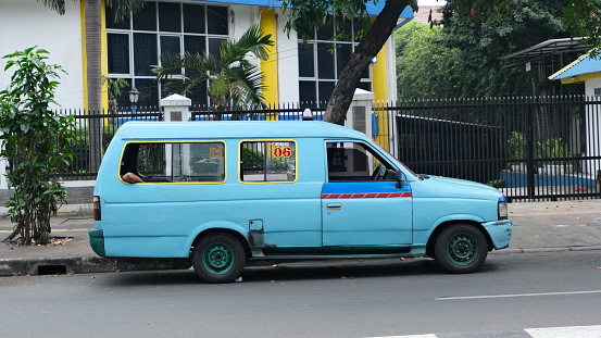 Jakarta, Indonesia - July 31 2023: An old minibus as public transport parked on the side of road, waiting for passenger