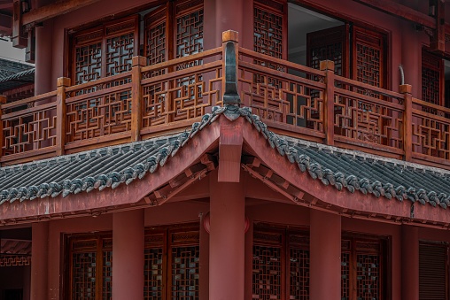 An ornate red Chinese temple with a grand entranceway featuring a painted black and red fence