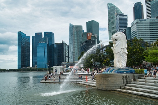 Singapore, June 14, 2019. Aerial view of the skyline of Singapore during a beautiful sunny day with the financial district in the distance. In front people are visiting the famous Merlion fountain at Marina Bay. Singapore is located in Southeast Asia.