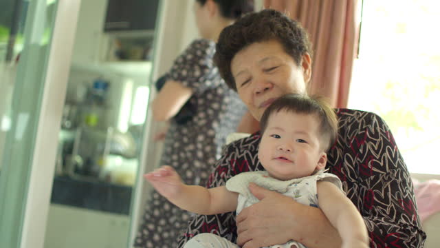 An Asian grandmother holding her 8-month-old grandson with heartfelt love