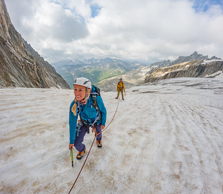 Mittelberg, Austria - June 24, 2020: Rope team mountaineering with crampons on glacier Sexegertenferner towards Sexegertenspitze and mountain snow panorama with blue sky in Tyrol Alps. The tour to the mountain Sexegertenspitze is a high mountain tour.