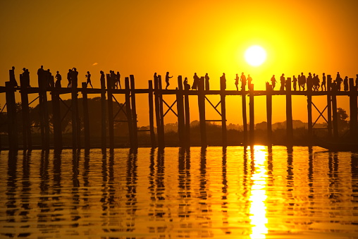Mandalay. Myanmar. November 22, 2016. Locals and numerous tourists watch the sunset on the famous wooden bridge over Lake Taungtaman.