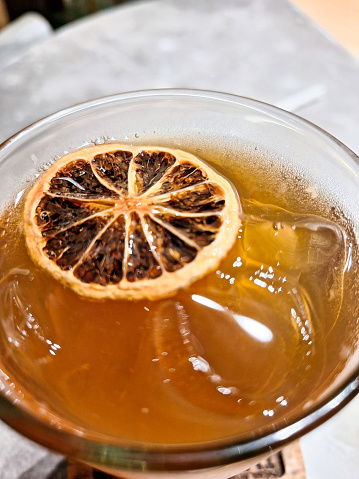 Top view of an iced lemon tea with dried lemon at the top of a table