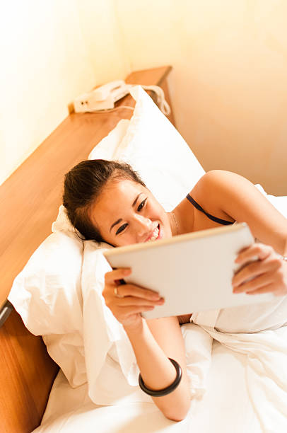 istock young asian girl plays with her tablet on the bed 158045850