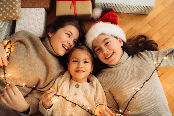 istock Three Girls having fun lying on floor surrounded with Christmas presents 1580486866