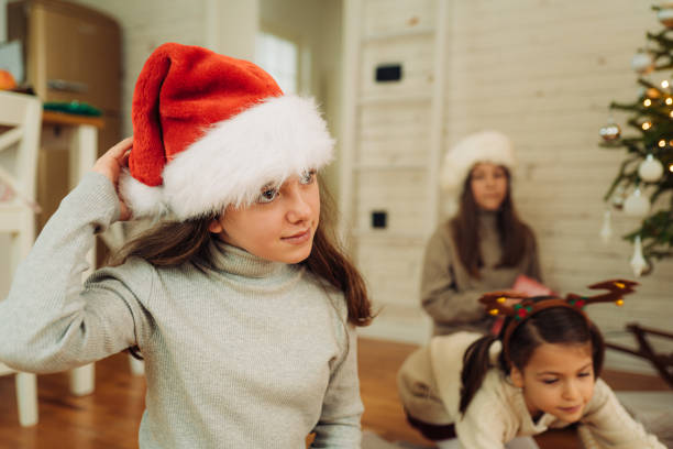istock Three girls having fun while decorating the Christmas tree at home 1580490580