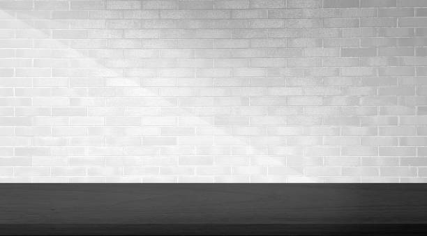 istock empty black minimal table for product displayed. black oak wooden table at foreground on white brick background with soft light beam. elegant scene for business advertising. 1580540010
