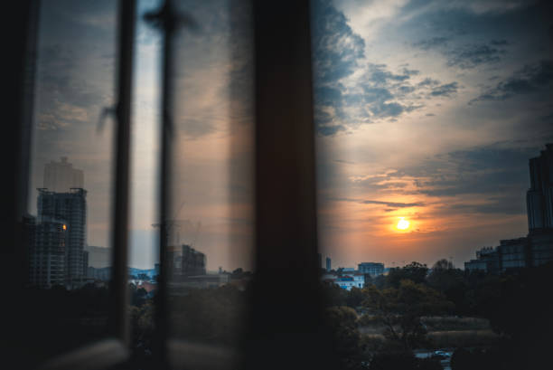 istock Sunset looking through window at city with reflection on window with sunset sun 1580567447