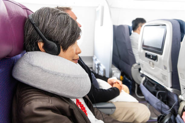 istock Asian woman with comfortable neck pillow relaxing during longhaul airplane flight 1580665821