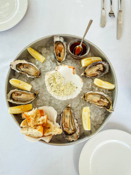 istock Appetizing fresh oysters with lemon on the deep dish on ice. Cheese with spices 1580674329