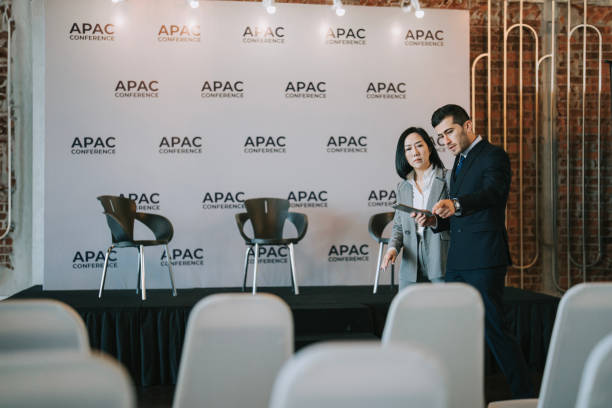 istock Asian Chinese businesswoman final check going through programme details with banquet hall manager before the business conference seminar begin 1580739281