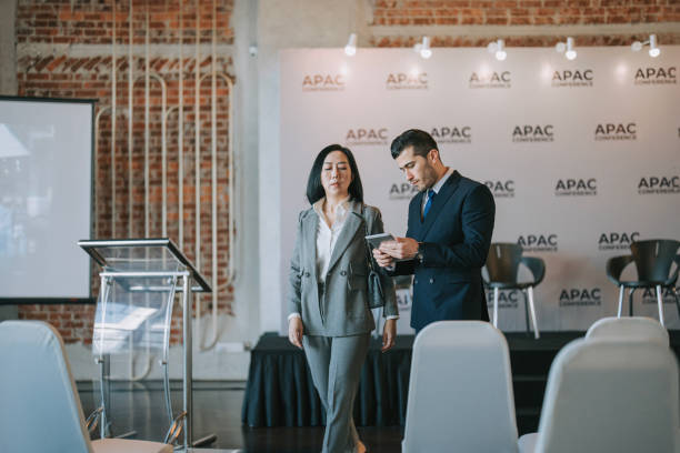 istock Asian Chinese businesswoman final check going through programme details with banquet hall manager before the business conference seminar begin 1580739287