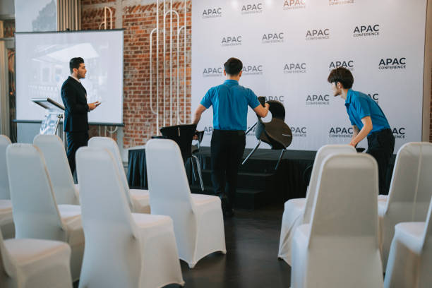 istock Asian Banquet hall manager coordinating crew arranging VIP speaker seat on stage before the business conference seminar begin 1580741472