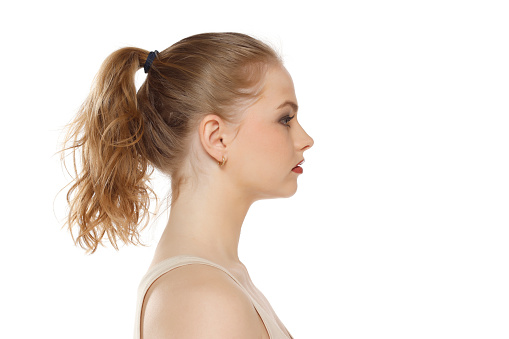 Profile, side view of beautiful serious blonde woman with tied hait on a white studio background