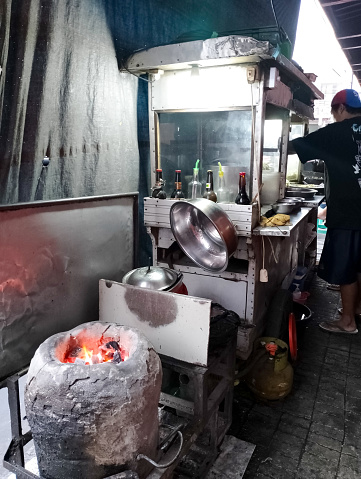 Sukabumi, West Java, Indonesia - July 25, 2023: A fried noodle seller in Indonesia who is getting ready to make fried noodles on an old charcoal stove with a smoldering charcoal fire