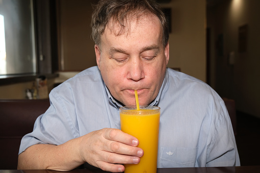 Autistic male drinking orange juice