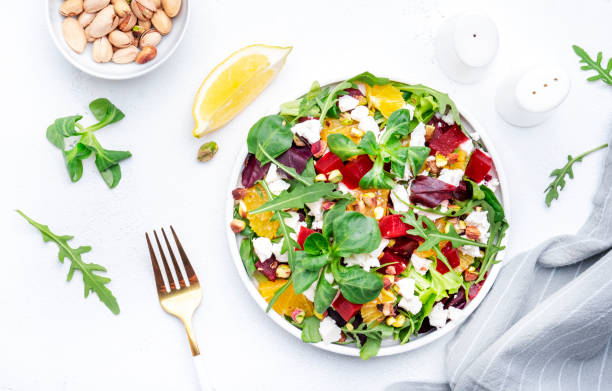 istock Beetroot and white cheese salad with arugula, lettuce,  orange and pistachios on white table. Fresh useful dish for healthy eating 1580771858