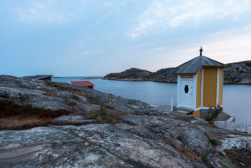 The yellow building of a sauna built on the edge of the rocky coast by the sea, Smogen, Bohuslan, Sweden