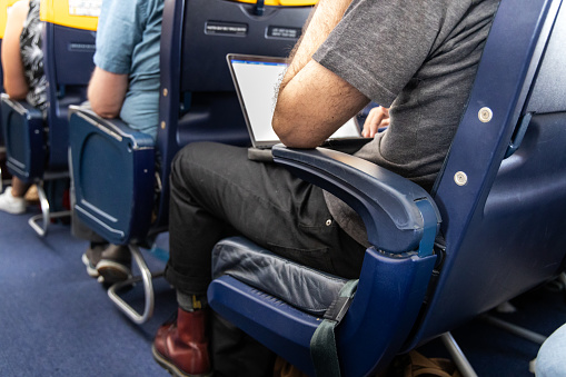 Flight passenger using laptop during long-haul flight in economy class to catch up with work
