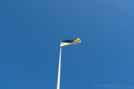 The flag of Ukraine on a mast, flying in the wind, against a blue sky