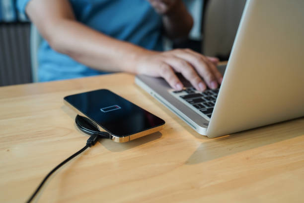 istock Charging mobile phone battery with wireless charging device in the table. Smartphone charging on a charging pad. Mobile phone near wireless charger Modern lifestyle technology concept 1580791101