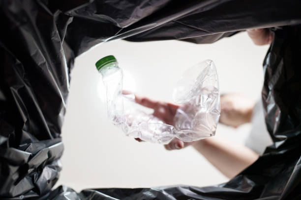 istock Image from inside yellow recycling bag of man throwing empty plastic bottle in recycling bin Home recycle eco green zero concept. 1580791109