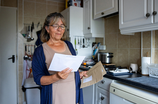 Portrait of a senior woman at home checking a letter in the mail - domestic life concepts