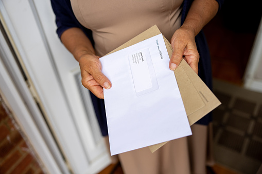 Close-up on a woman at the front door of her house holding her mail - domestic life concepts