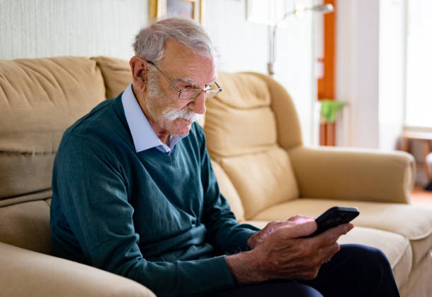 istock Senior man sitting at home using his cell phone 1580816283