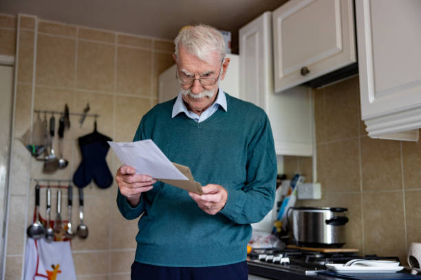 istock Senior man at home reading a letter in his mail 1580816647
