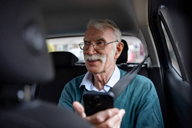 compartilhamento de carro de homem idoso usando um aplicativo de celular em seu celular - mobile phone seat belt text messaging smiling - fotografias e filmes do acervo