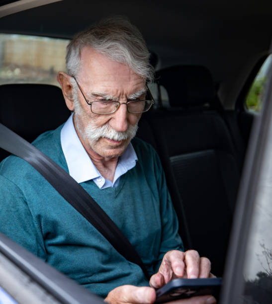 istock Senior man riding on a car and texting on his cell phone 1580816843